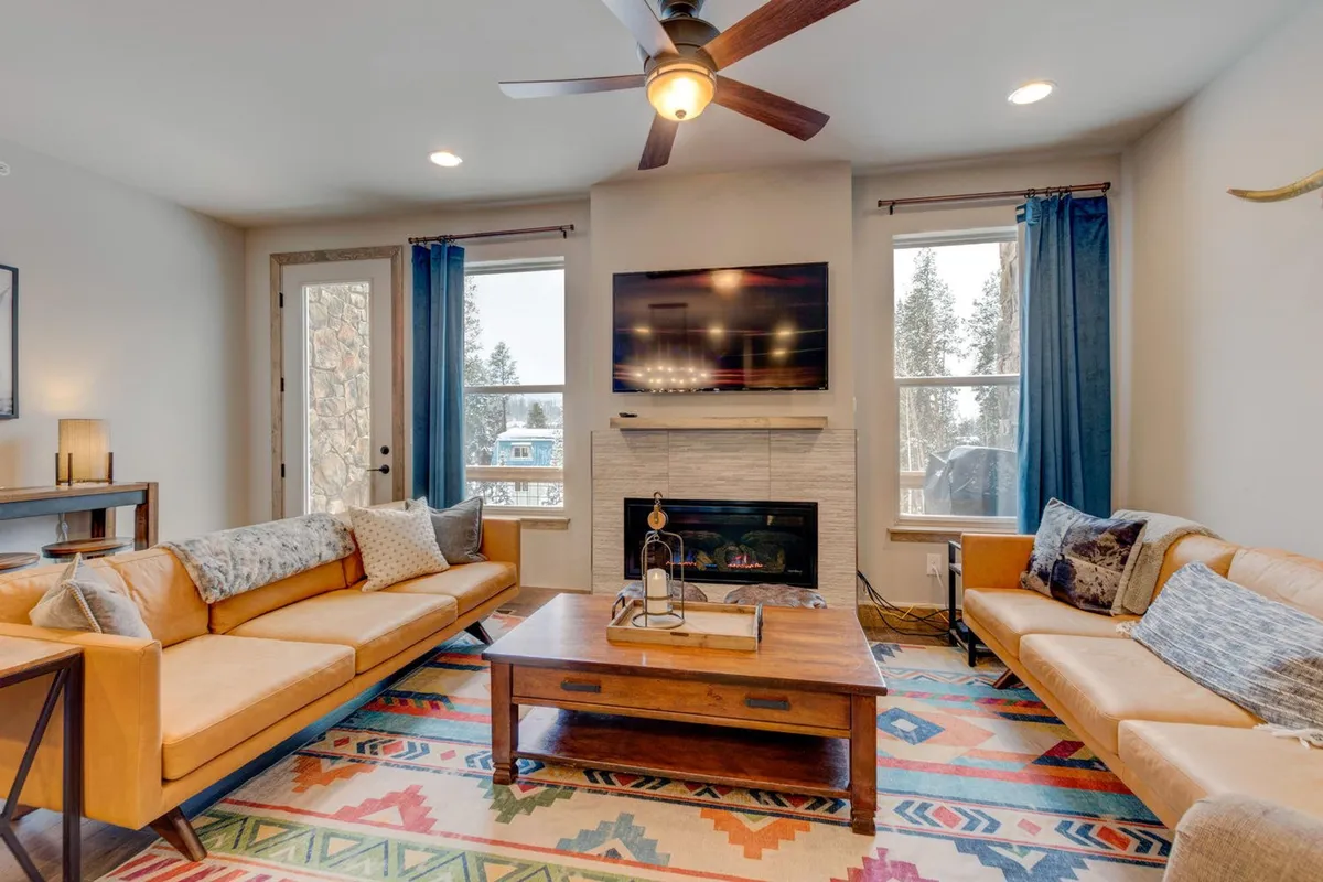 A cozy interior living room with leather sofas, a coffee table, fireplace, television, and a soft rug. The setup is ideal for relaxing or socializing after outdoor activities, and there's ample space for families and pets to unwind together.