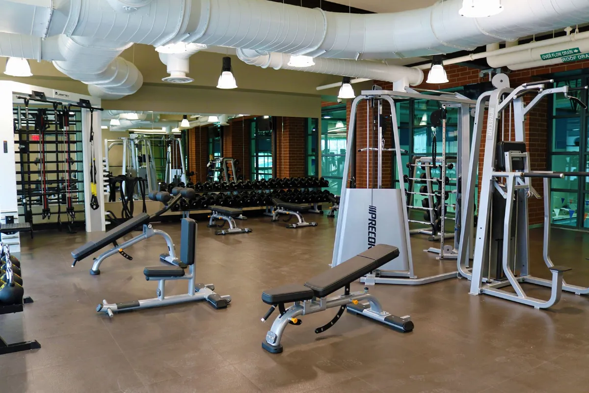 A bright, well-equipped fitness center with mirrored walls, a range of weightlifting equipment, and benches, designed for personal and group training sessions. The space is inviting and motivates guests to stay active during their stay, regardless of the weather outside.